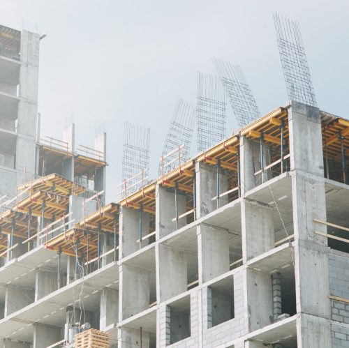 Cranes in the construction of high-rise buildings. Construction of floor coverings. Construction of a building made of solid concrete.